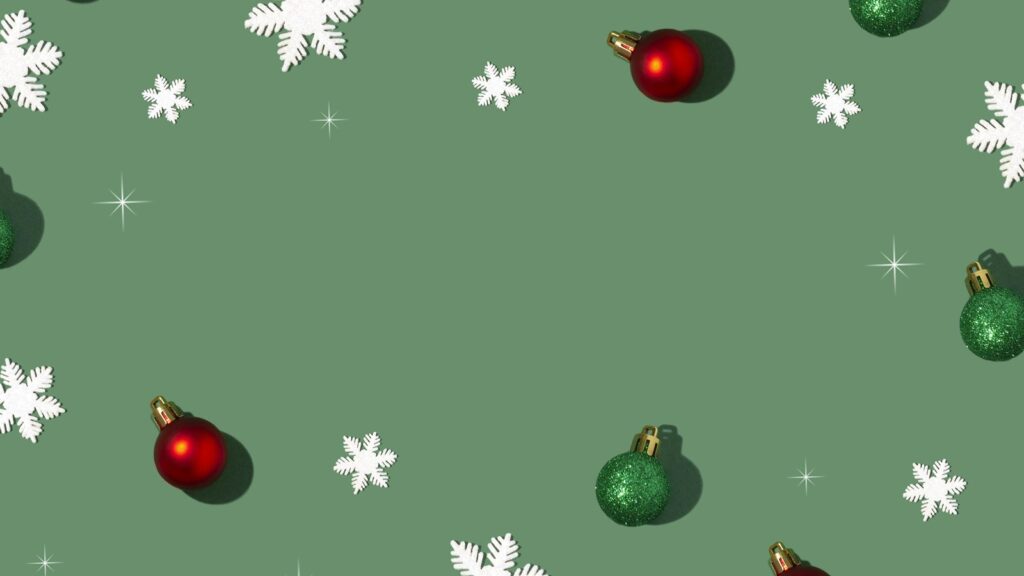 Red and green glitter baubles and white paper snowflakes scattered on a sage green background